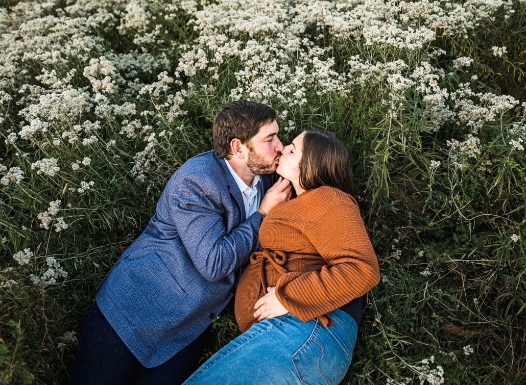 maternity couple kissing in wildflowers